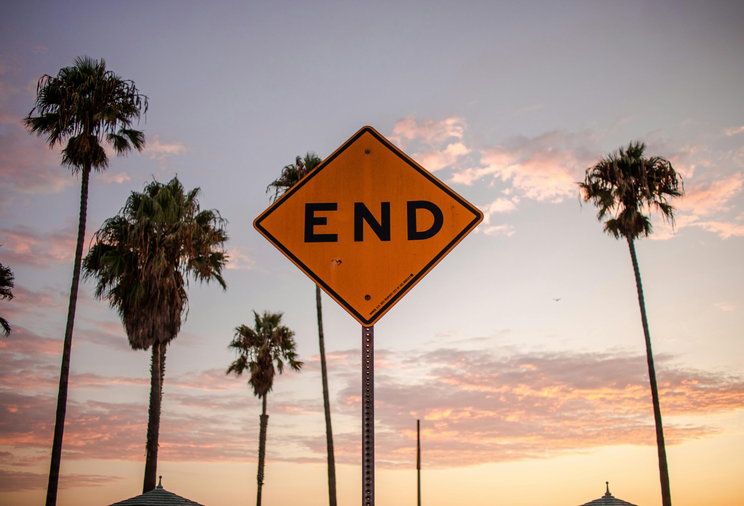 End sign amidst palm trees and sunset sky in Santa Monica, Los Angeles.