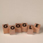 Wooden alphabet blocks forming the word 'Google' on a plain background, arranged playfully.