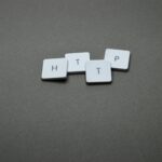 High-angle photo of keyboard tiles spelling HTTP on a dark background.