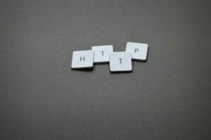 High-angle photo of keyboard tiles spelling HTTP on a dark background.