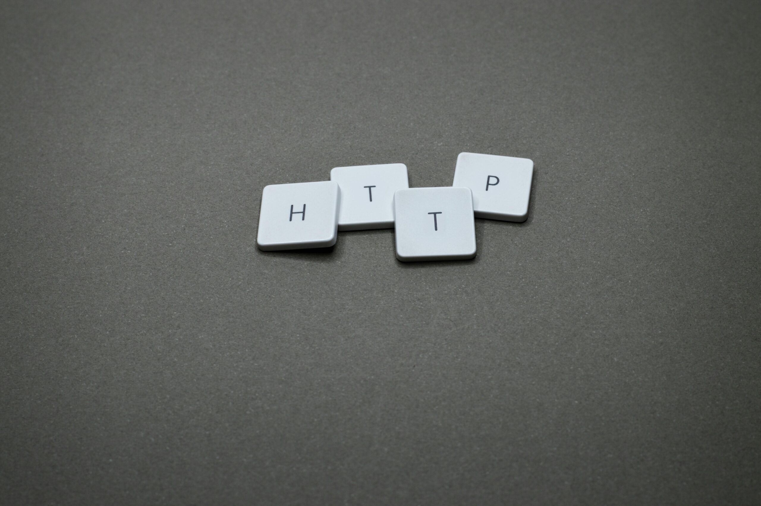 High-angle photo of keyboard tiles spelling HTTP on a dark background.