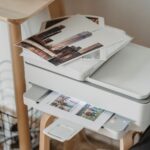 From above of images placed on printer on wooden table with cup of hot coffee at workplace