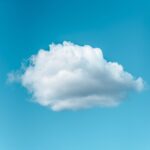 Low angle of lonely white fluffy cloud floating in blue sky in sunny day