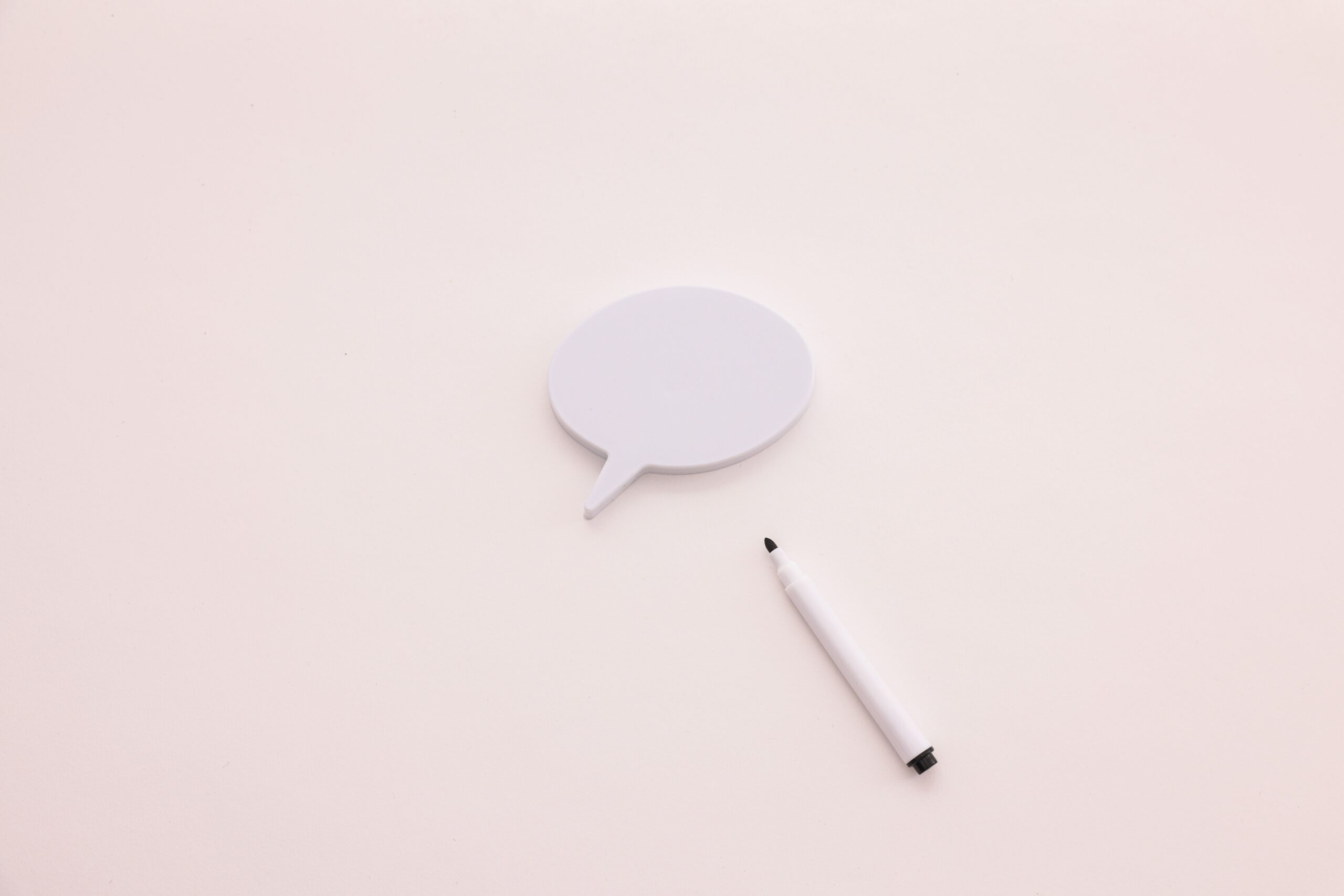 A minimalist speech bubble with a white marker on a clean white background, perfect for creative designs.