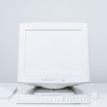 A minimalist white computer setup including monitor, keyboard, and mouse on desktop.