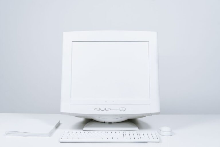 A minimalist white computer setup including monitor, keyboard, and mouse on desktop.