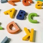 Bright and colorful wooden alphabet letters scattered on a white surface.