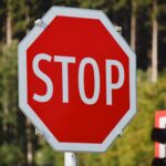 Close-up of a bright red stop sign against a background of lush green trees.