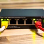Close-up of a TP-Link Ethernet switch with yellow, red, and white cables connected.